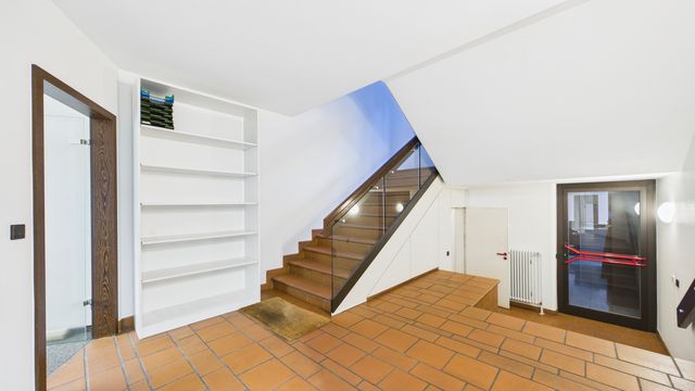 Innenliegendes Treppenhaus mit Zugang zur Tiefgarage, Treppe mit Glasgeländer und Fliesenboden